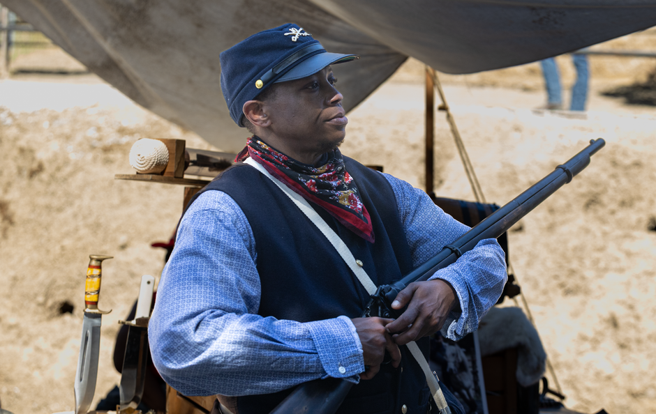 Civil War reenactor in Union uniform holding a musket under a canvas tent