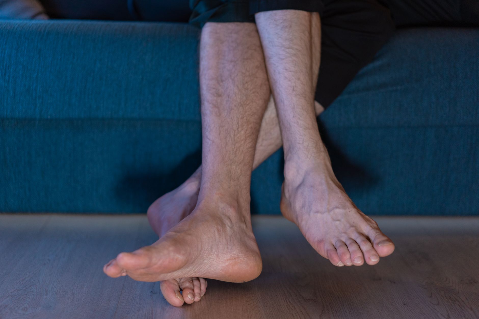 Close-up of a person sitting with crossed legs and bare feet, the position that makes a foot fall asleep